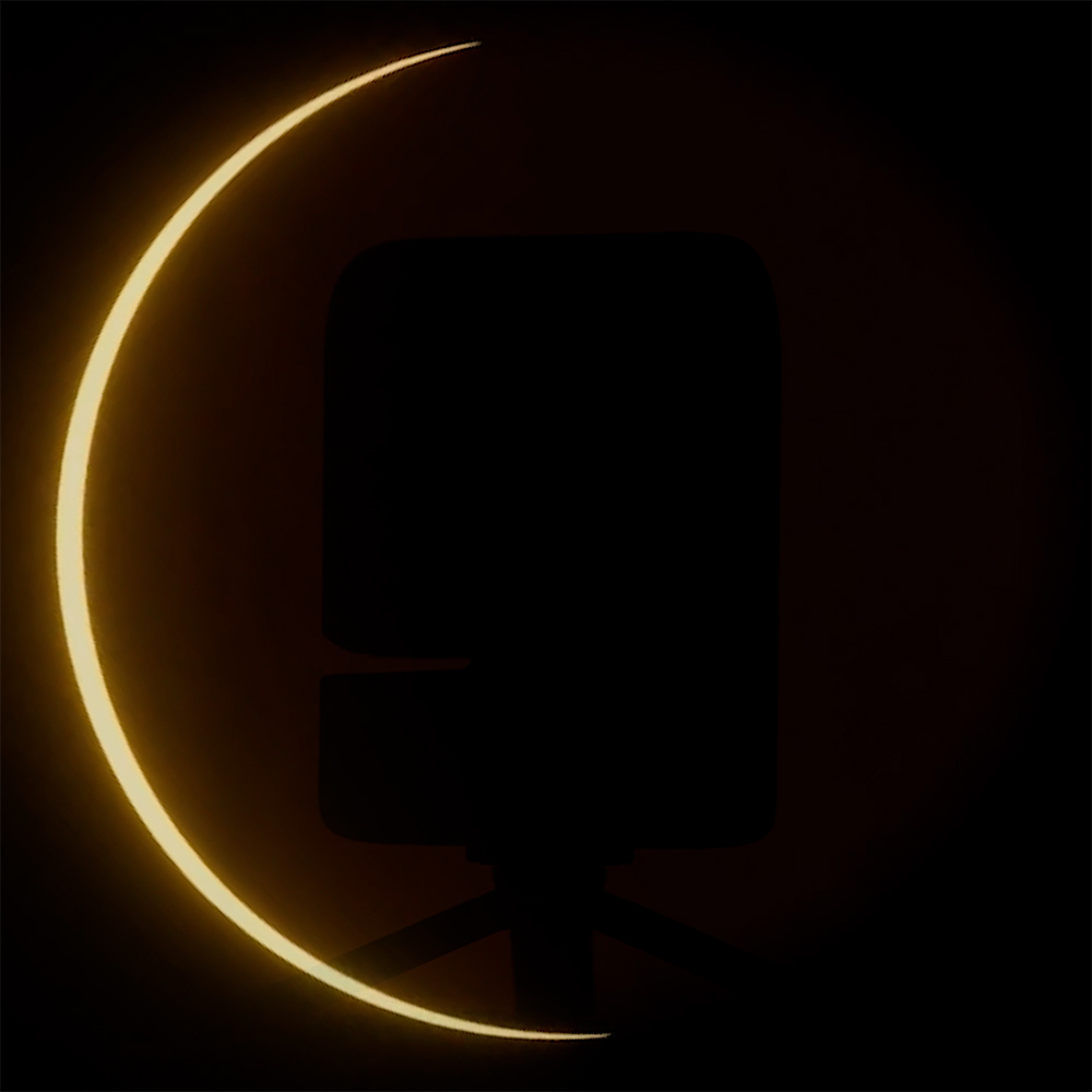 Image of the a silhouetted Seestar S30 Pro Eclipse Edition in front of a partial solar eclipse