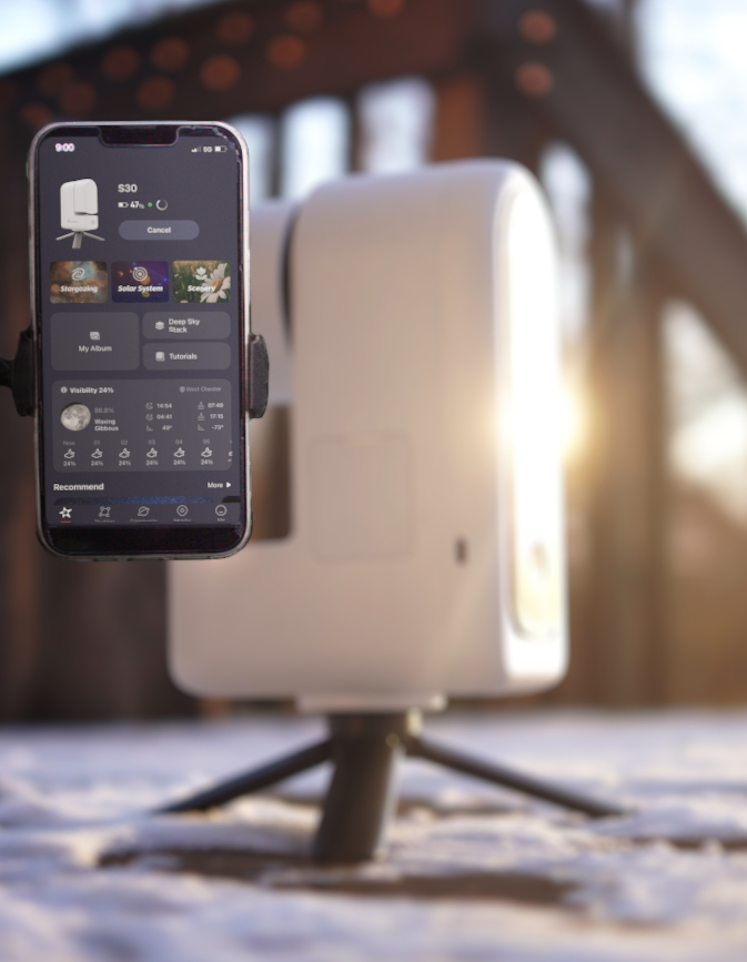 A phone showing the Seestar app, with the ZWO Seestar S30 out of focus in the background